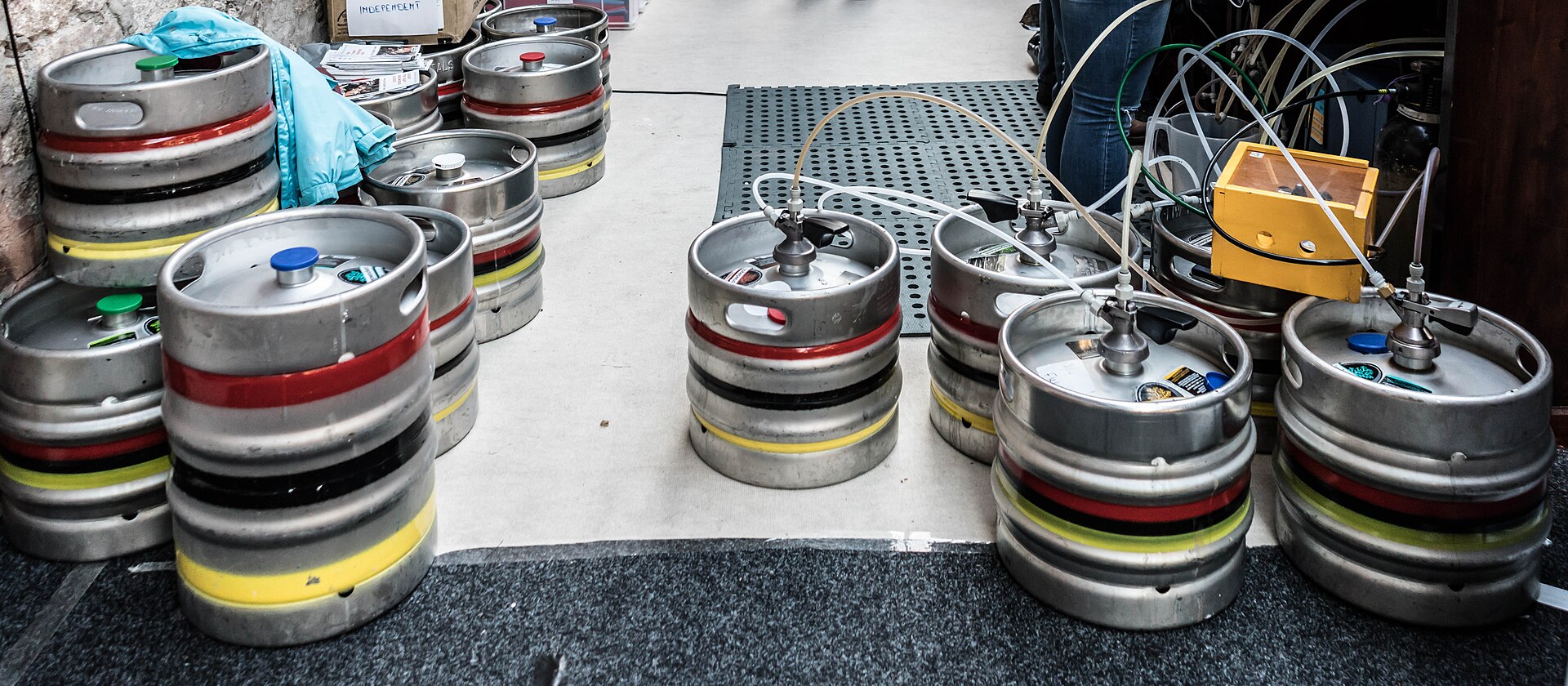 Festival guests sampling beer beside rows of brewery kegs