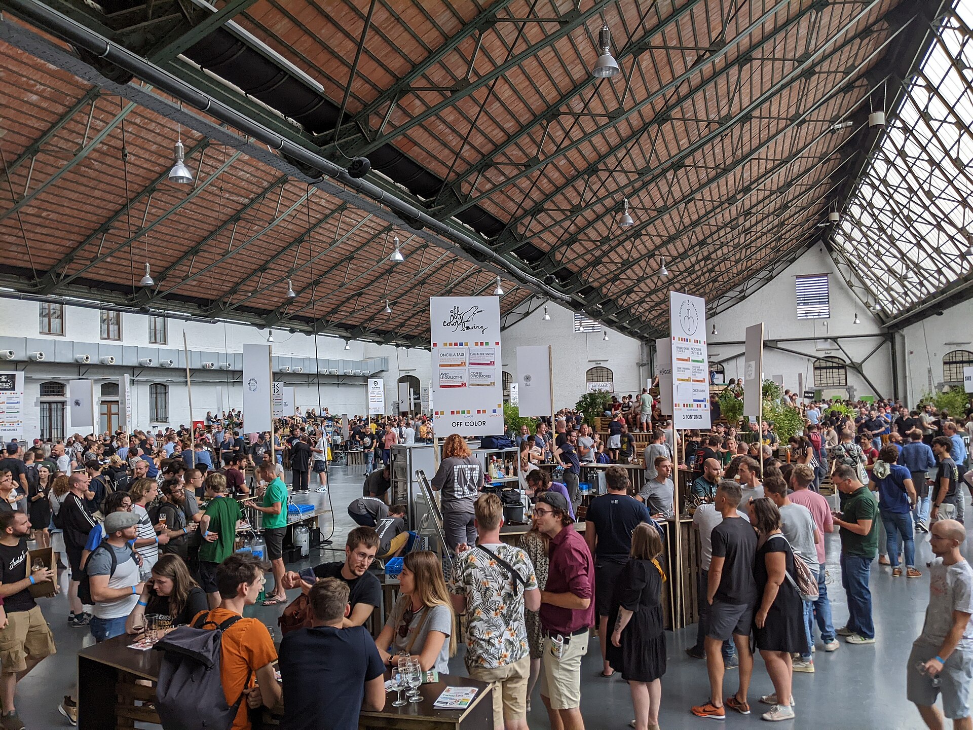 Crowds enjoying a Belgian beer festival inside a bright market hall