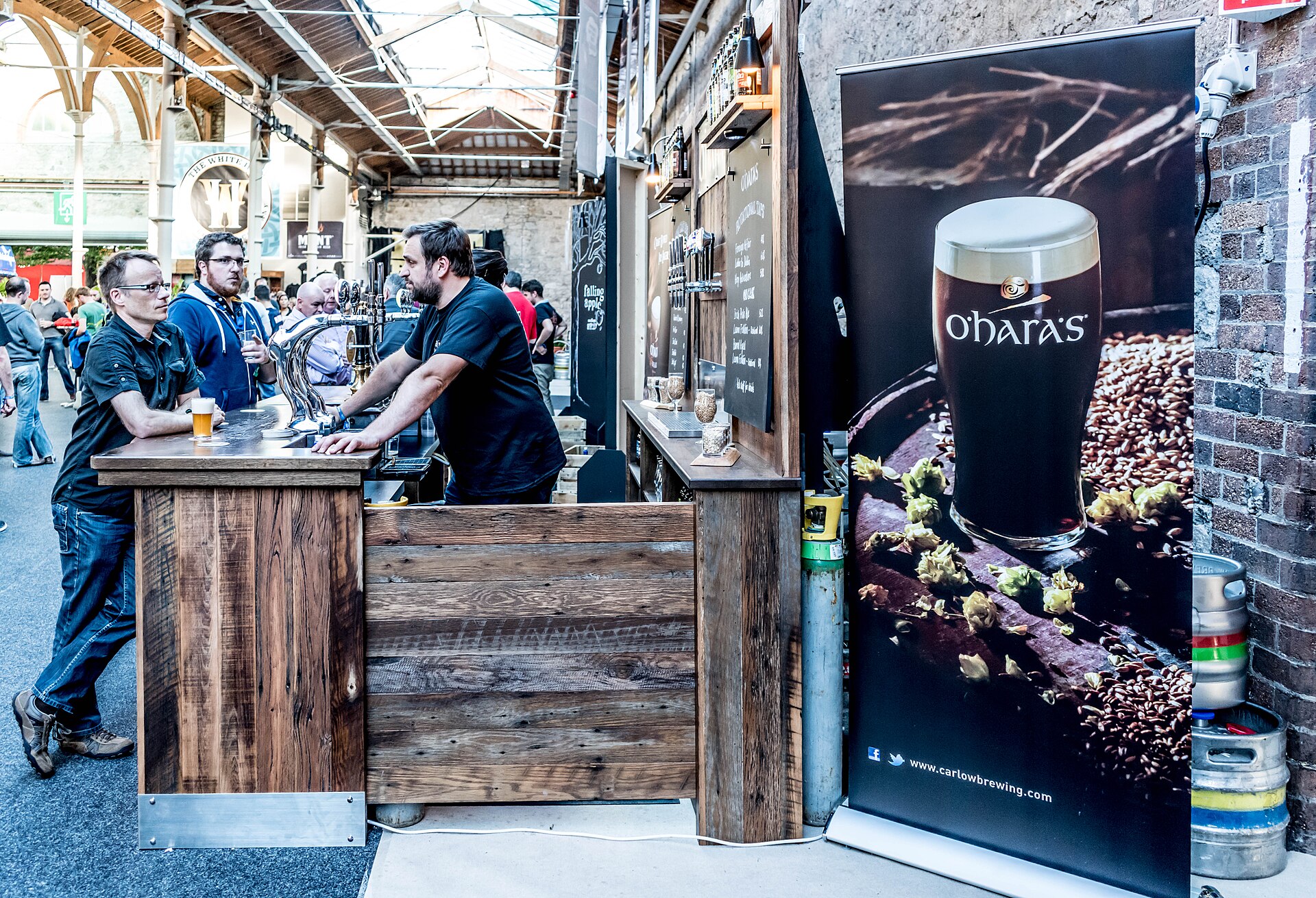 Guests talking over tasting glasses at a craft beer festival bar