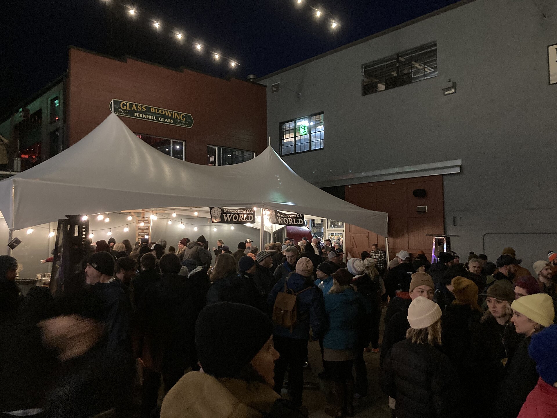 A nighttime craft beer festival crowd beneath outdoor lights
