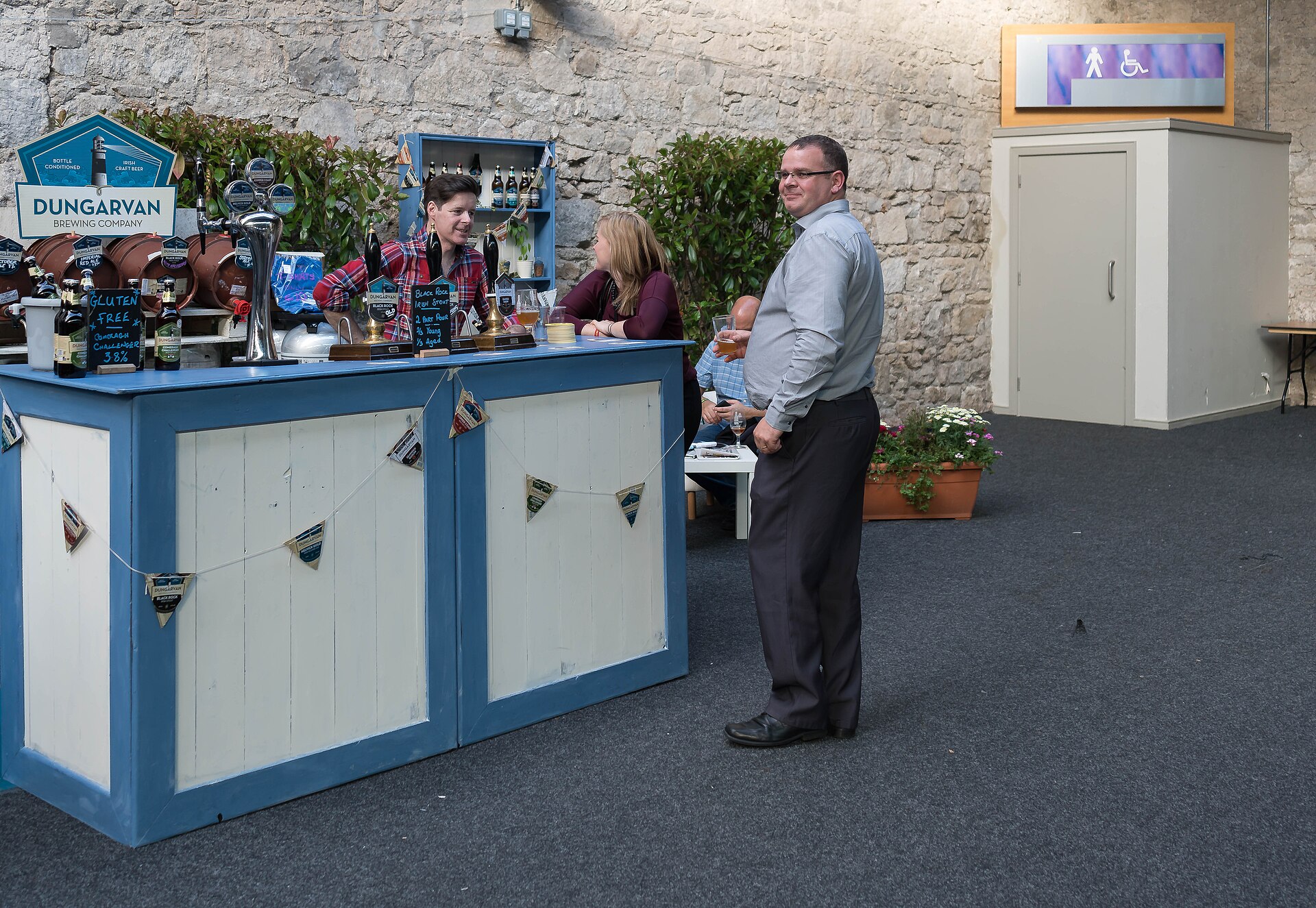 Guests chatting with a brewer at an outdoor festival bar